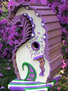 a purple bird house sitting on top of a wooden bench