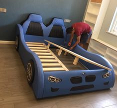 a man working on a bed frame in a room with blue walls and wood floors