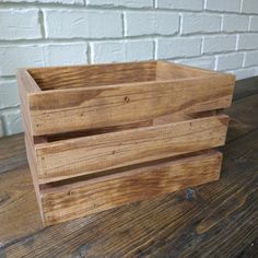 a wooden crate sitting on top of a wooden table next to a white brick wall