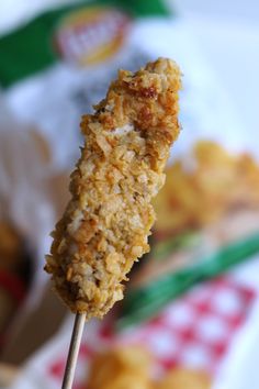 a close up of food on a toothpick with other foods in the background