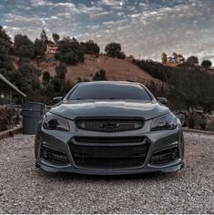 the front end of a gray car parked on gravel