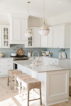 a large kitchen with white cabinets and an island