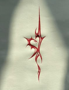 a red tattoo design on white paper with shadow from the person's arm and foot