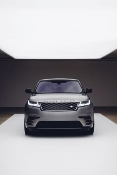 the front end of a silver range rover parked in an empty room with white walls