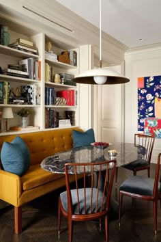 a living room filled with furniture next to a dining table and bookshelf full of books