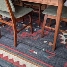 a wooden table with four chairs and a rug on the floor in front of it