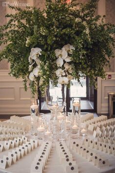 a centerpiece with flowers and candles on a table in a room filled with tables