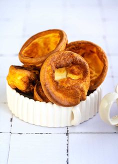 some food is in a white bowl on the floor next to a cup and saucer