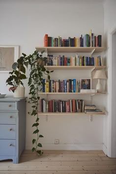 a bookshelf filled with lots of books next to a blue chest of drawers