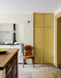 a kitchen with yellow cabinets and a wooden chair