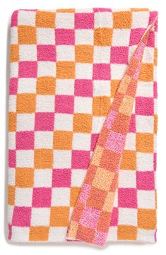 an orange and pink checkered towel on top of a white blanket with a pink tie hanging from it