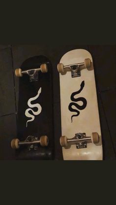 two skateboards sitting next to each other on the ground, one with a snake painted on it