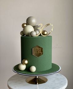 a three tiered green cake with white and gold decorations on it's top