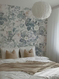 Serene bedroom showcasing the Faded Luxury Wallpaper, which features large-scale floral prints in soft shades of white, blue, and green. The design creates a tranquil backdrop for a bed dressed in light beige pillows and a textured cream throw, enhancing the room's calm and restful ambiance. Wallpaper Backgrounds Room, Wallpaper Backgrounds Bedroom, Wallpaper Feature Wall Bedroom, Wallpaper Accent Wall Bedroom, Blue Wallpaper Bedroom, Wallpaper In Bedroom, Faded Background, Costal Bedroom, Blog Wallpaper