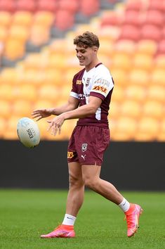 a young man holding a rugby ball on top of a field