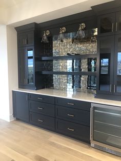 an empty kitchen with black cabinets and silver counter tops, along with wood flooring