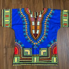 This Unique African Dashiki Shirt Is A Must-Have For Fashion Enthusiasts Seeking A Touch Of Cultural Flair. With Its Vibrant Multicolor Design And Unisex Fit, This Shirt Is Perfect For Both Men And Women. Made Of 100% Cotton, It Is Comfortable And Breathable, Making It Ideal For Everyday Wear. The Shirt Comes In A Size Small But Designed To Fit Oversized. It Features A Blue Character Design That Adds A Pop Of Color And Style To Any Outfit. This Shirt Is Perfect For Casual Occasions And Can Be Pa Blue Character Design, African Dashiki Shirt, Dashiki Shirt, African Dashiki, New Vintage, Blue Orange, Color Pop, Everyday Wear, Tunic Tops