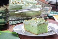 a slice of green cake on a plate with a bottle of beer in the background