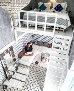 a woman sitting on top of a white couch under a bed next to a staircase