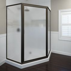 an empty bathroom with a corner shower stall in the center and wood flooring on the other side