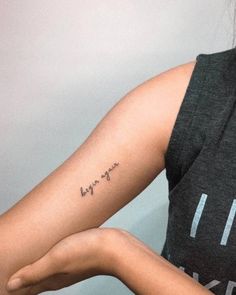 a woman with a small tattoo on her arm and the word love is written in cursive writing