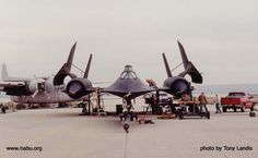 two fighter jets parked on top of an airport tarmac next to other vehicles and people