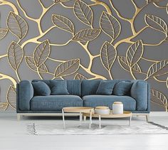 a blue couch sitting in front of a wall with gold leaves on it's side