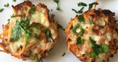 four mini pizzas with cheese and herbs on them sitting on a white table top