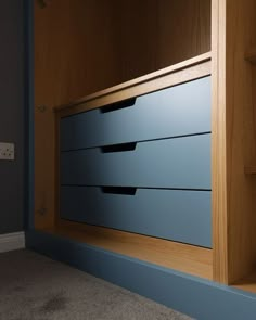 an empty room with blue drawers and carpeted flooring on the side, in front of a wooden wall