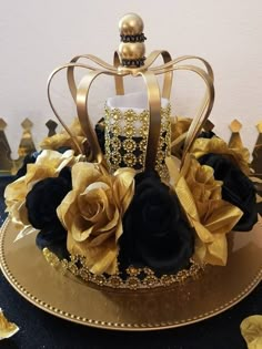 a gold and black cake with roses on it's top, sitting on a plate