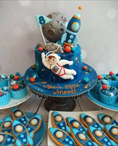 a space themed birthday cake and cupcakes on a table