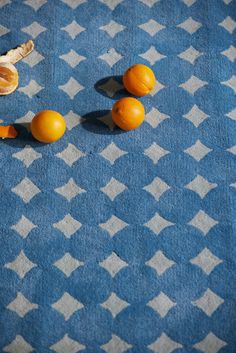 three oranges on a blue and white checkered tablecloth next to an peeled banana