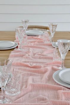 the table is set with plates and silverware on it, along with pink linen