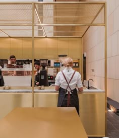 two people standing in front of a counter with food on it and one person behind the counter