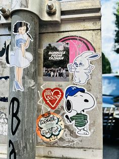 stickers on the side of a street pole in front of parked cars and people