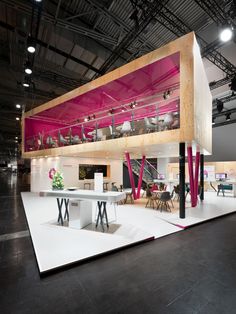 a large open space with tables and chairs on the floor in front of a pink wall