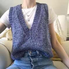 a woman sitting on a couch wearing a sweater vest