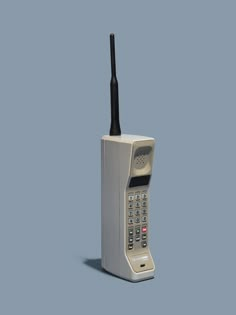 an old cell phone sitting on top of a white box with a black antenna attached to it