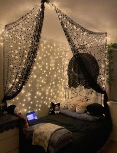 a bedroom decorated with fairy lights and netted bedspread, laptop on the bed