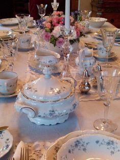 the table is set with dishes, silverware and candlesticks for an elegant dinner