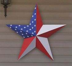 a red, white and blue star hanging on the side of a building next to a light