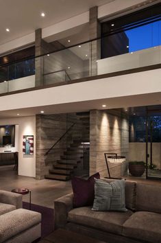 a living room filled with lots of furniture next to a stair case in front of a window