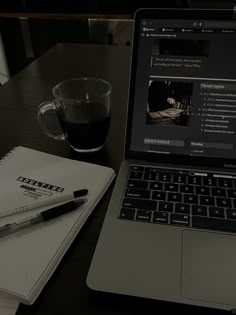 an open laptop computer sitting on top of a desk next to a cup of coffee