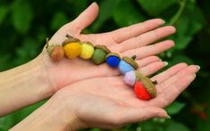 a person's hand holding a toy caterpillar with multicolored wool