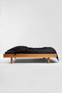 a wooden bed with black sheets on it