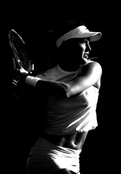 a black and white photo of a woman holding a tennis racket in her hands