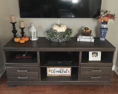 a flat screen tv sitting on top of a wooden entertainment center next to a vase filled with flowers