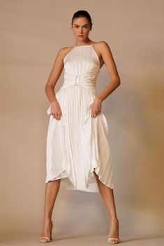 a woman in a white dress posing for the camera with her hands on her hips