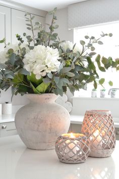 a vase with flowers and candles sitting on a counter top next to a candle holder