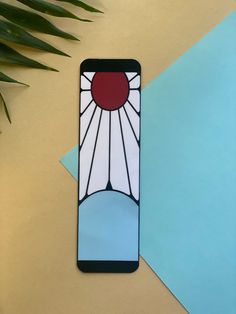 a cell phone with a stained glass design on it sitting next to a blue envelope